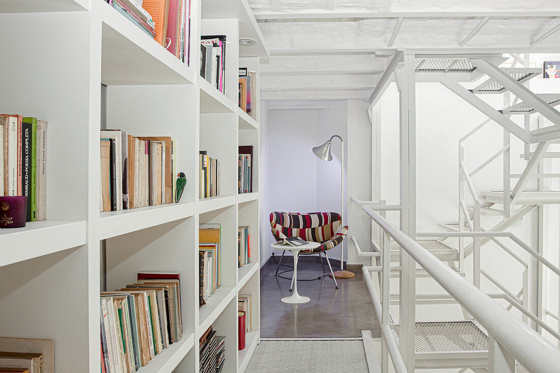 Bookcase, side table and easy chair on mezzanine with white iron structure