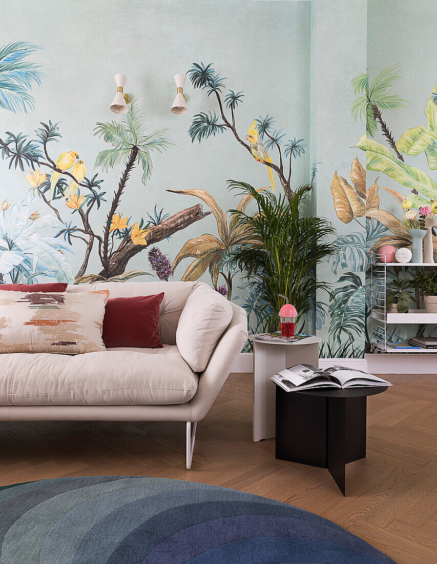 Naturweißes Sofa vor Tapete mit botanischem Motiv im Wohnzimmer