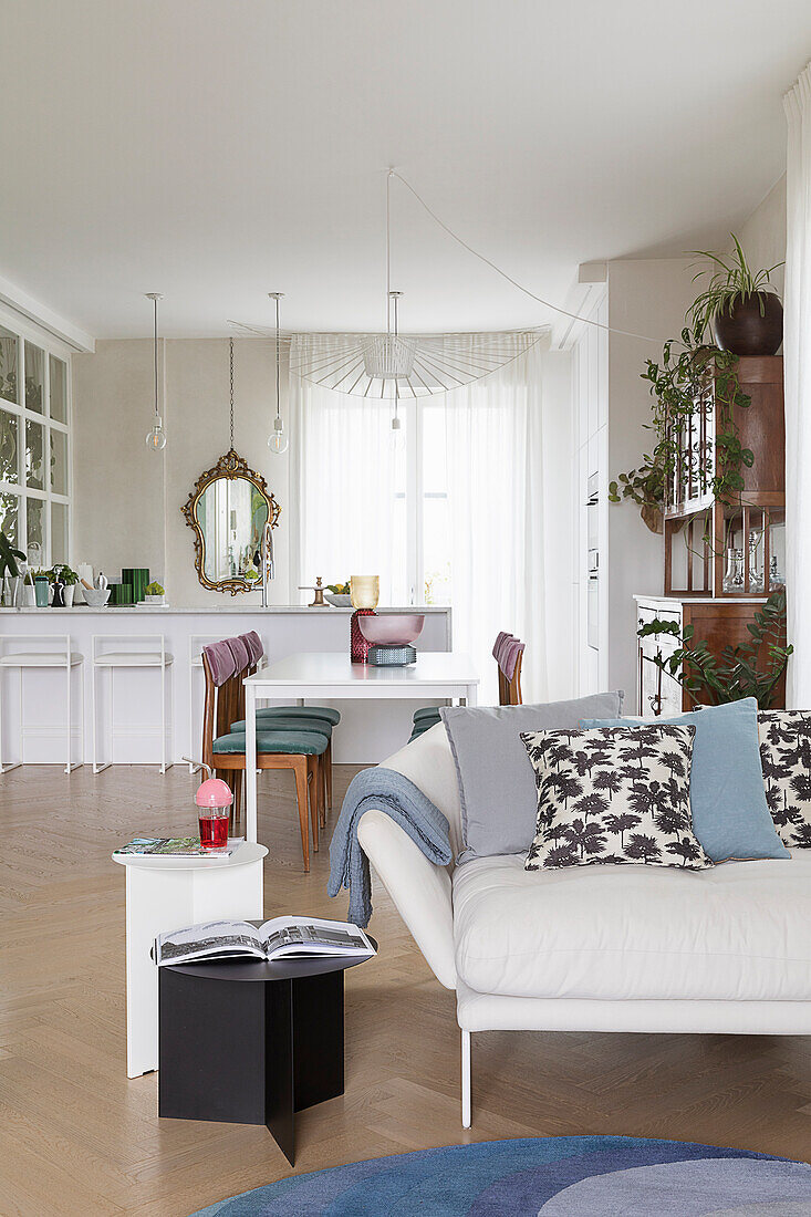 Naturweißes Sofa mit Kissen und Beistelltische in offenem Wohnraum
