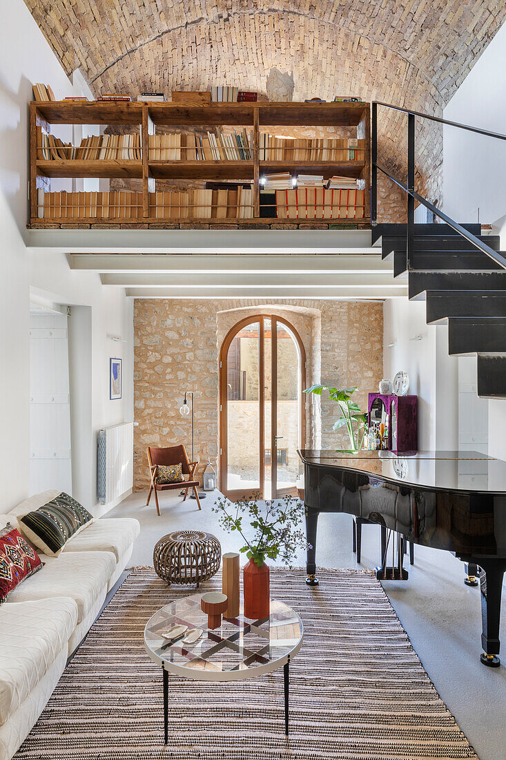 Klavier im Wohnraum mit Natursteinwand und Bücherregal auf Galerie