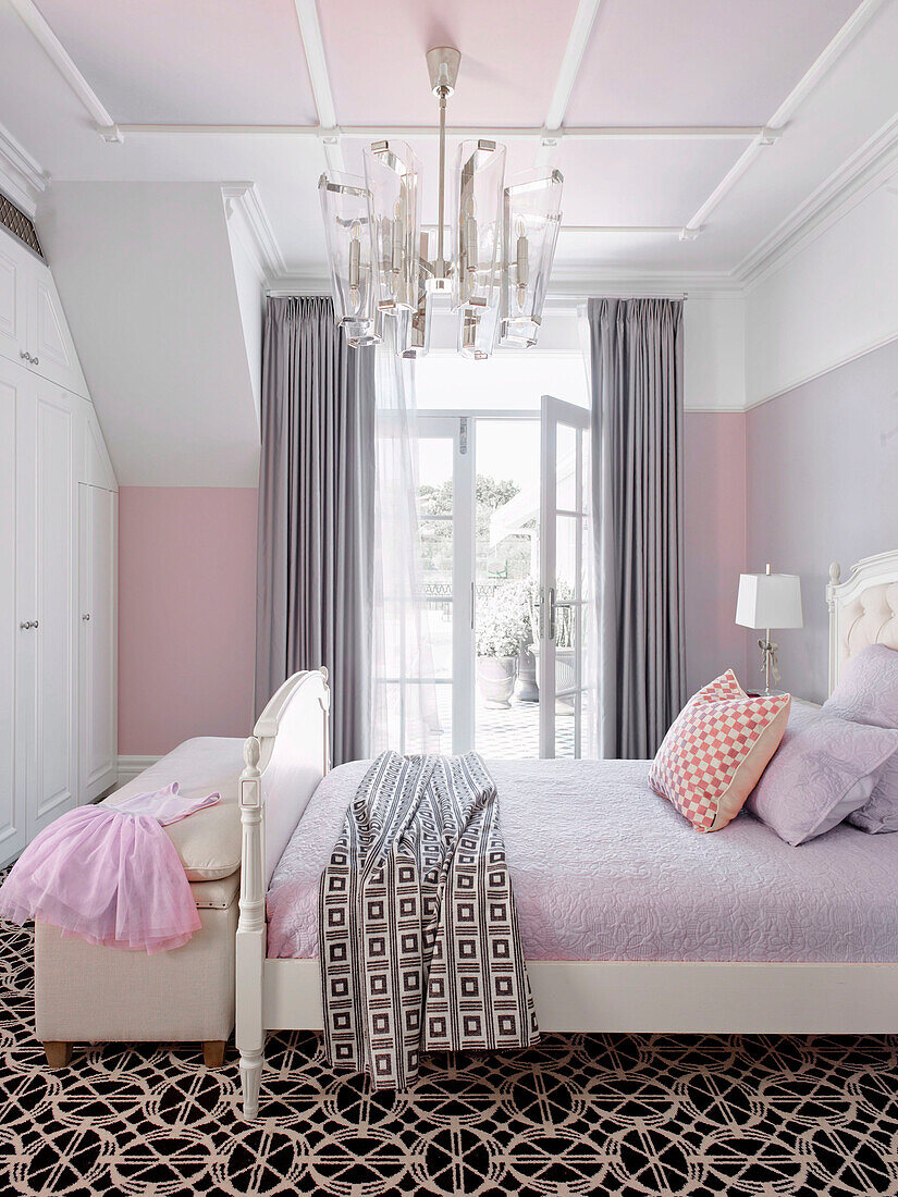 Elegant girls bedroom in white and pink tones with double bed and dressing bench