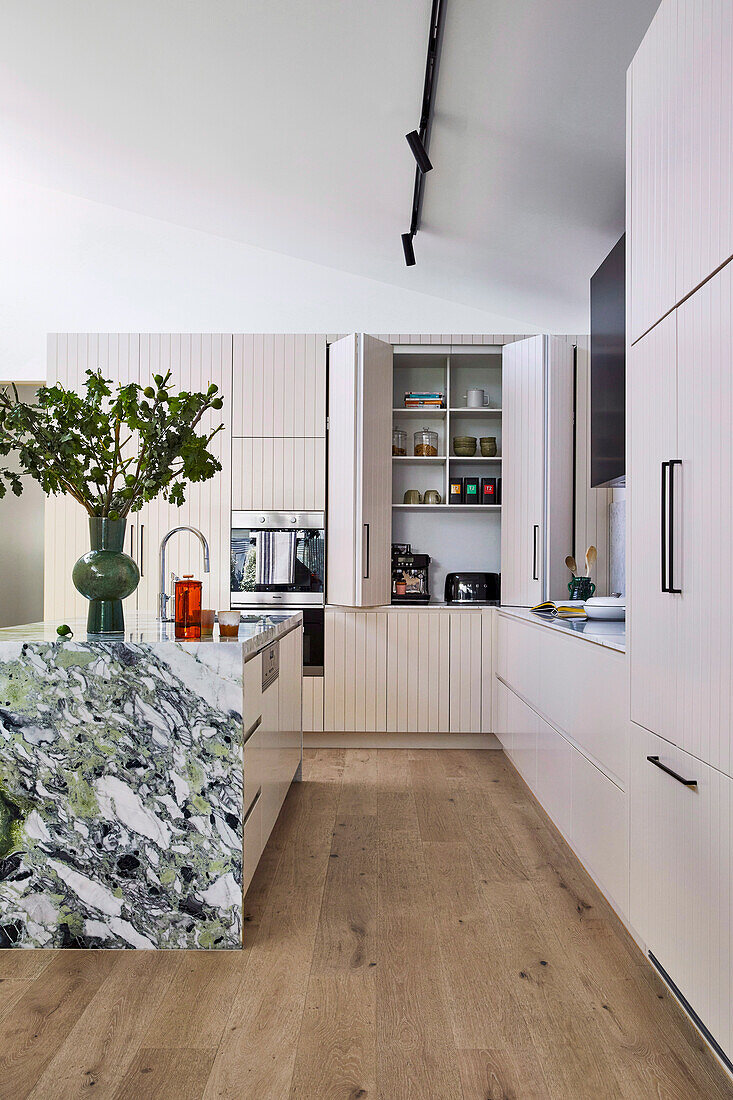 Einbauküche mit ausklappbaren Türen und Kücheninsel mit grüner Marmorverkleidung