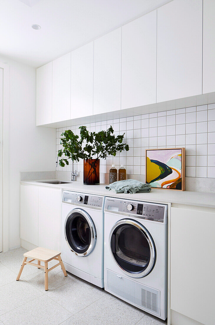 Waschraum mit weißen Schränken, Waschmaschine und Trockner