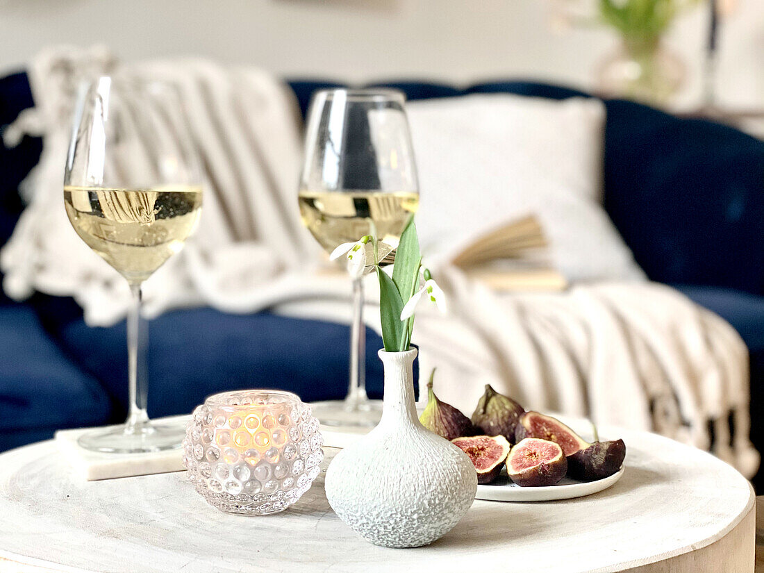 Flower, crystal bowl, wine glasses and fig on a coffee table