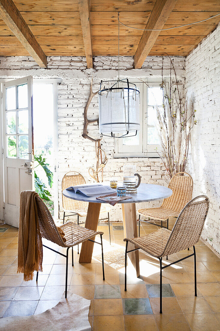 Runder Tisch mit Stühlen und Gartenzugang im Zimmer mit weiß getünchter Ziegelwand