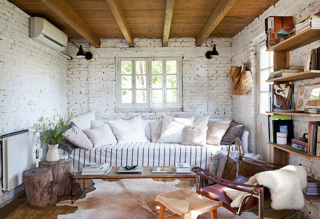 Sofa mit Kissen und Regal im Zimmer mit weiß getünchter Ziegelwand