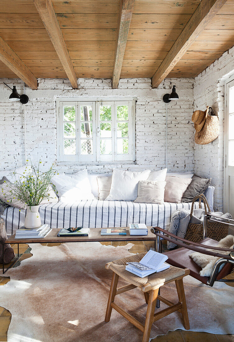 Sofa mit Kissen und Couchtisch im Zimmer mit weiß getünchter Ziegelwand