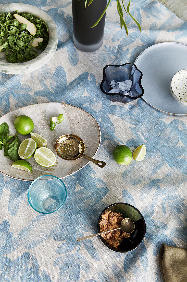 Limes, salad and small bowls on blue and white tablecloth