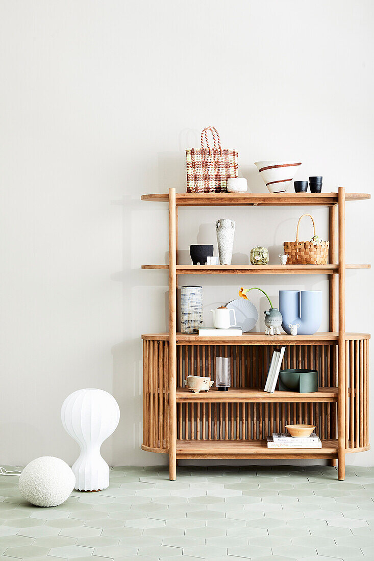 Wooden shelf with decorative objects, floor vase next to it
