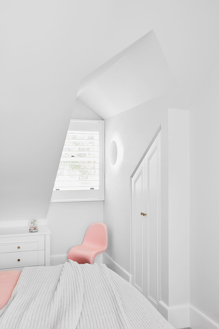 Bedroom in white, built-in wardrobe and pale pink chair