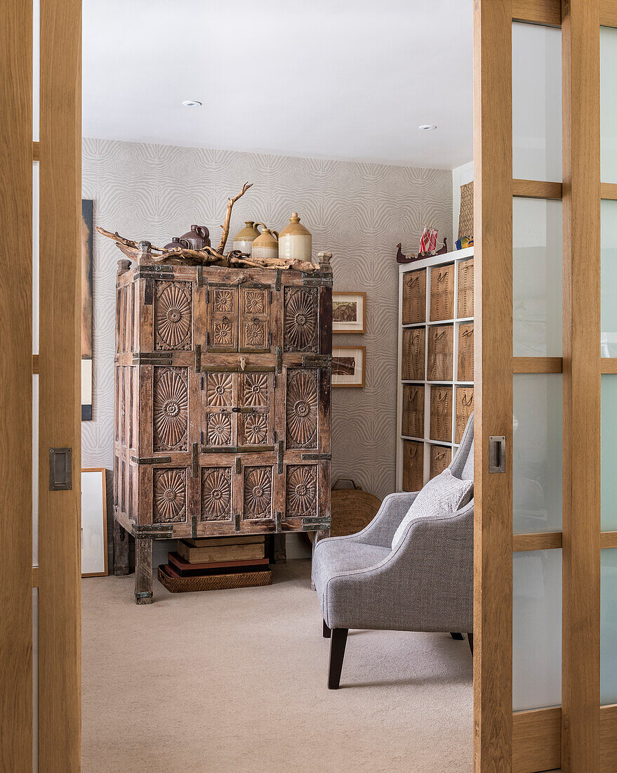 View through slidiing doors into home office with lots of wall shelving and an old wooden chest from Oman