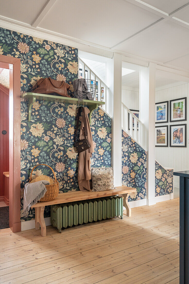 Bench and coat rack in the hallway with blue floral patterned wallpaper