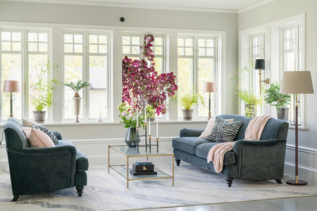 Coffee table with flowers and grey velvet sofas in bright living room