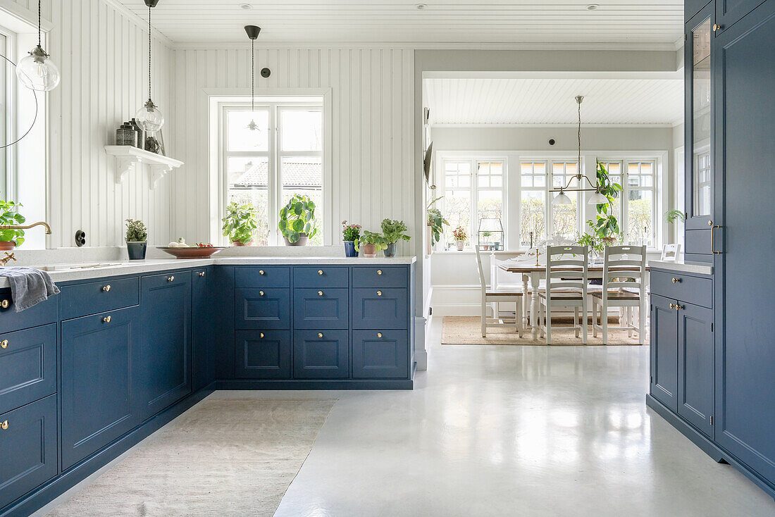 Schränke mit blauen Fronten in der Küche mit weiß gestrichener Holzverkleidung