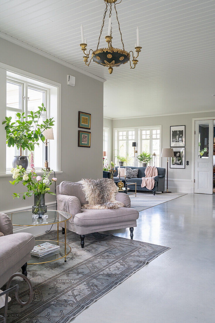 Light grey upholstered armchairs and coffee table with flowers in bright TV room
