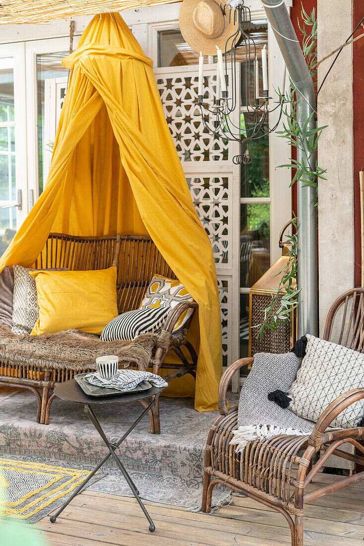 Rattan sofa with yellow canopy on the terrace