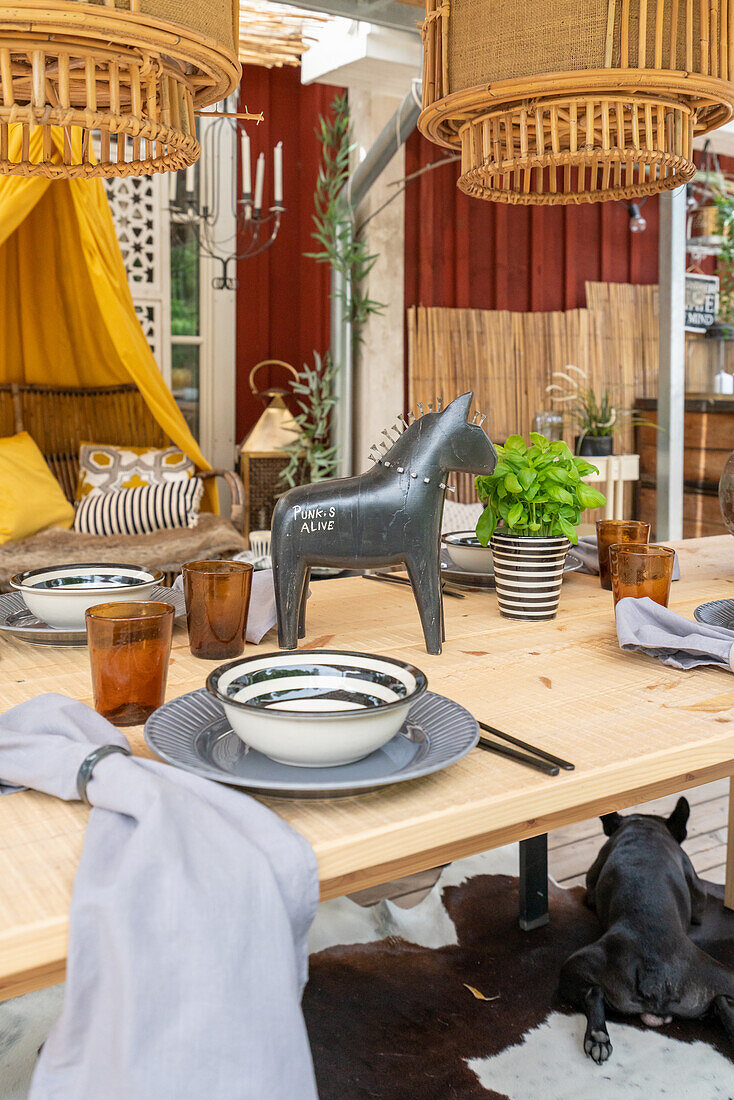 Gedeckter Esstisch mit Pferdefigur, darüber Bambus-Hängelampen