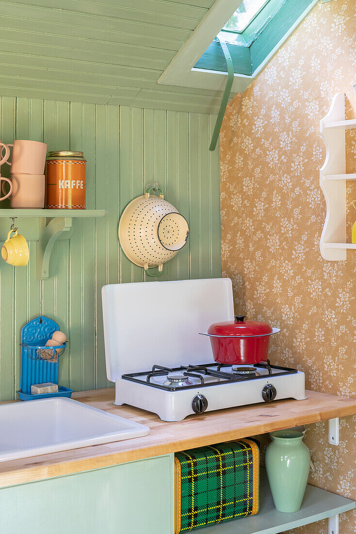 Portable gas hob in colourful retro kitchen with mint green wall panelling