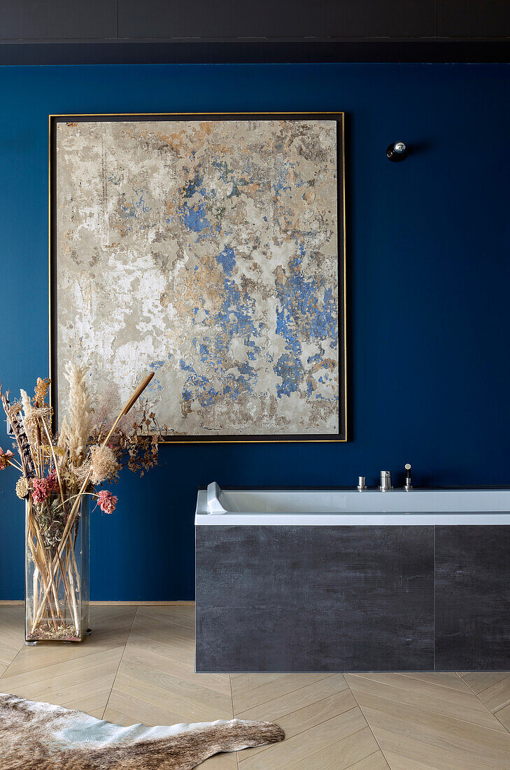 Bathtub below artwork on dark blue wall