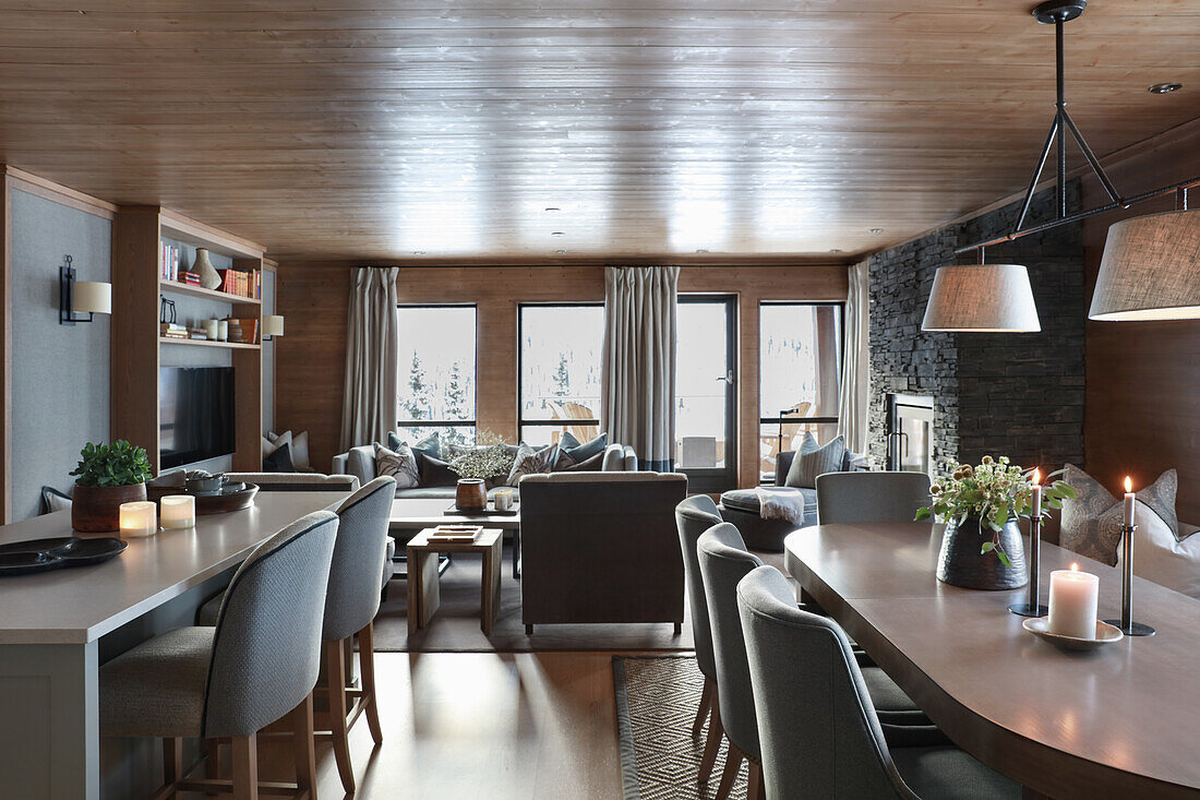 Kücheninsel, ovaler Esstisch, im Hintergrund Lounge in elegantem Wohnraum mit Holzverkleidung