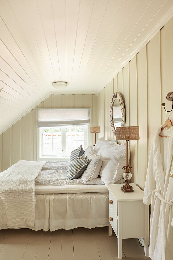Small bedroom with panelled walls and sloping ceiling