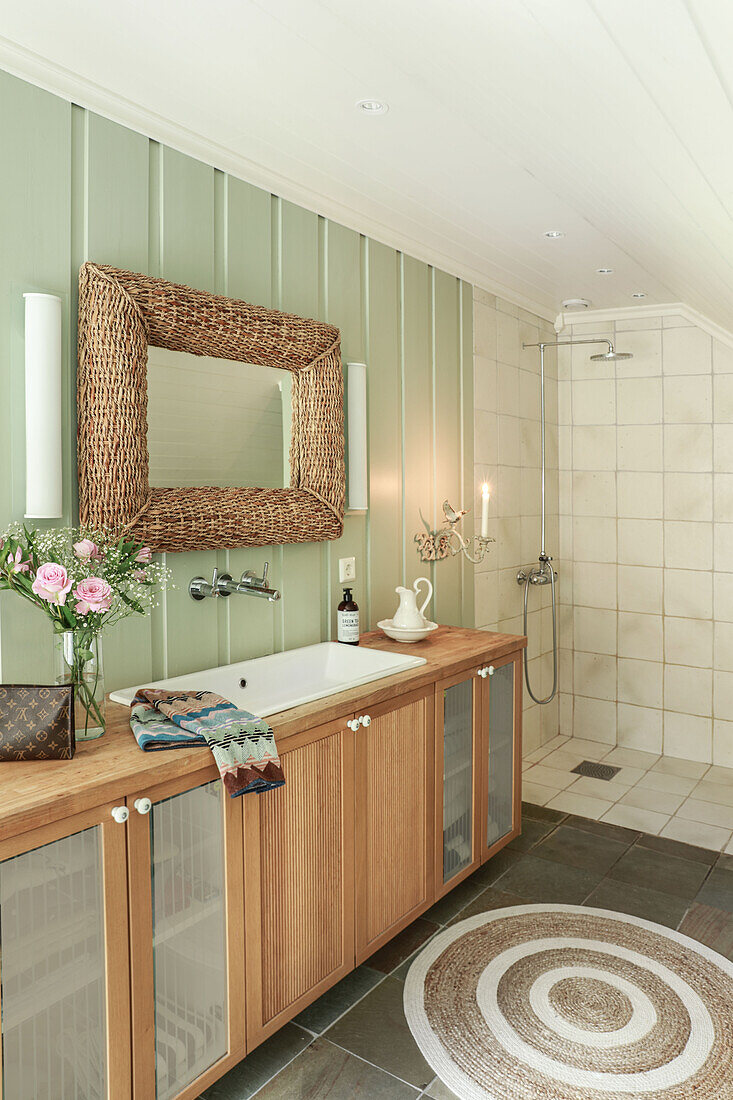 Mirror with wicker frame above long washstand in bathroom