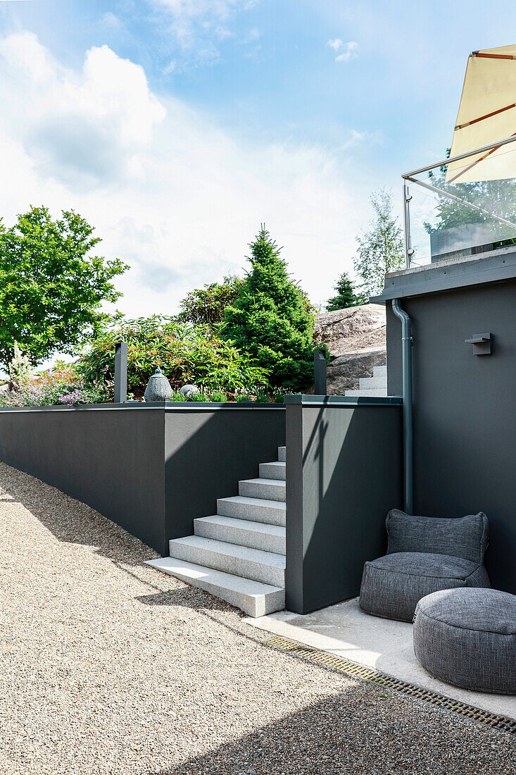 Stairs leading to a modern garden with grey walls and lounge furniture