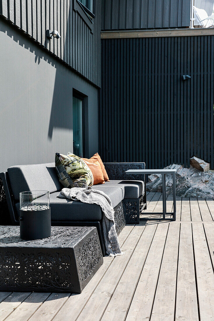 Modern lounge furniture on terrace decorated in dark grey adjoining house