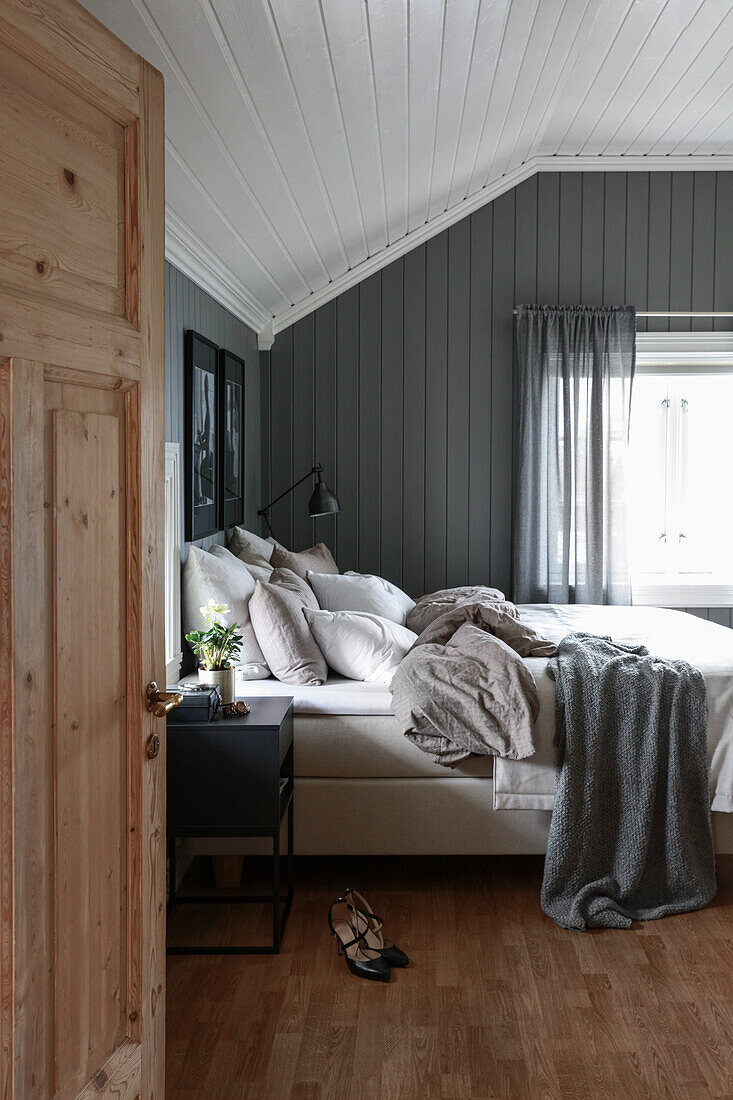 Blick ins Schlafzimmer mit Doppelbett und grau gestrichener Holzverkleidung