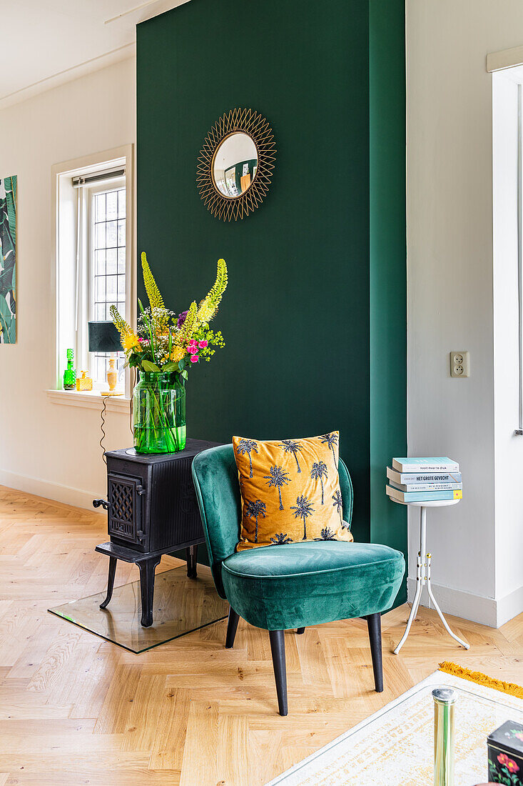 Retro velvet easy chair and cast iron stove in front of dark green wall