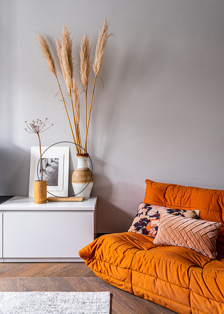 Orange two-seater sofa next to low sideboard