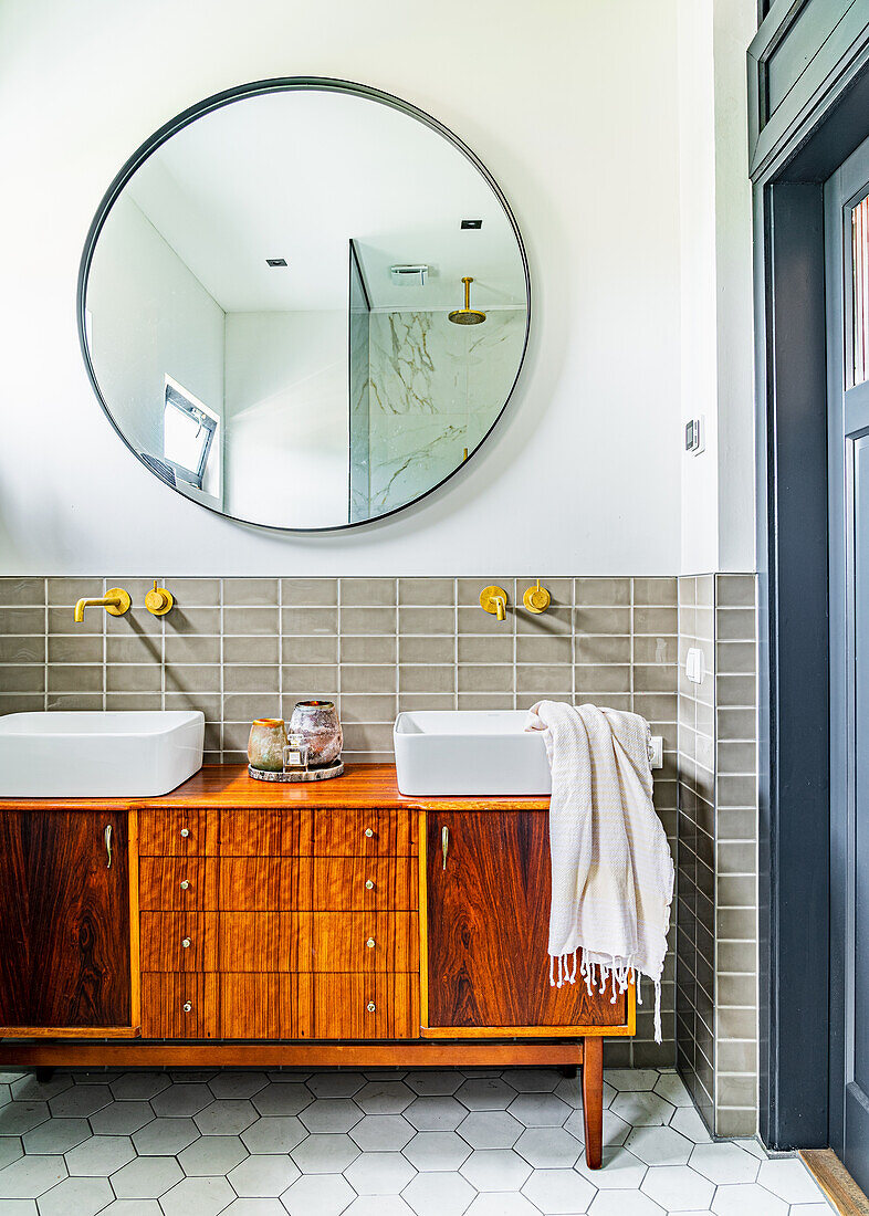 Retro Waschtischmöbel mit Aufsatzbecken vor Wandfliesen, darüber runder Spiegel