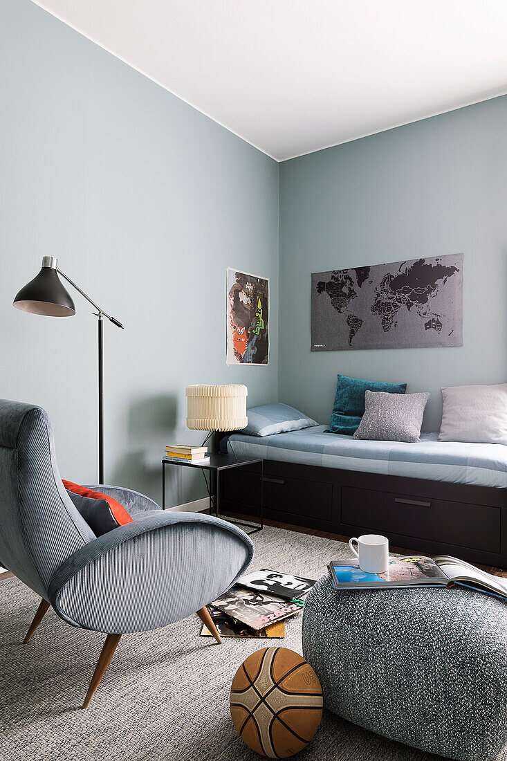 Bett, Polstersessel und Sitzpouf im Jugendzimmer mit blauen Wänden