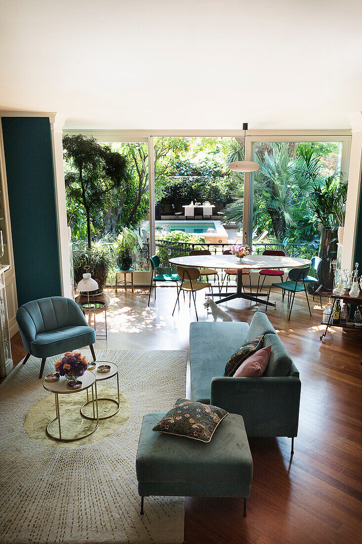 Offener Wohnraum mit grünen Wänden und Sitzmöbeln, Essbereich vor Glasfront