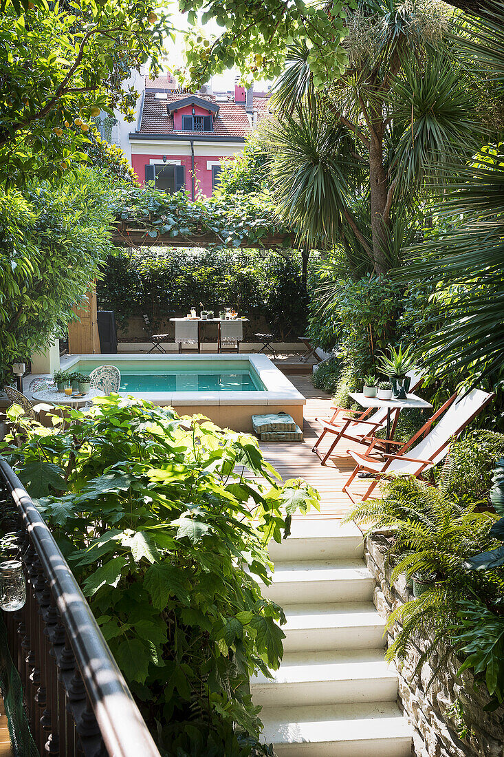 Treppe führt zur Terrasse mit Liegestühlen und Schwimmbecken