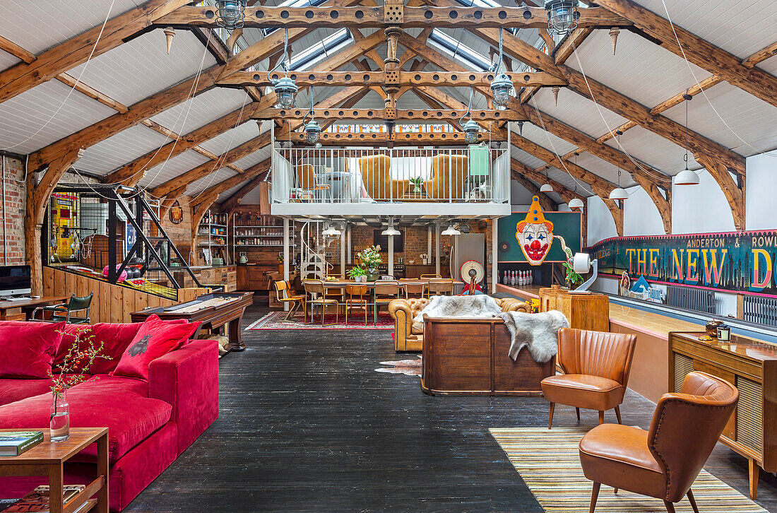 Open, eclectic living room with red velvet sofa and a bowling alley lane on the right