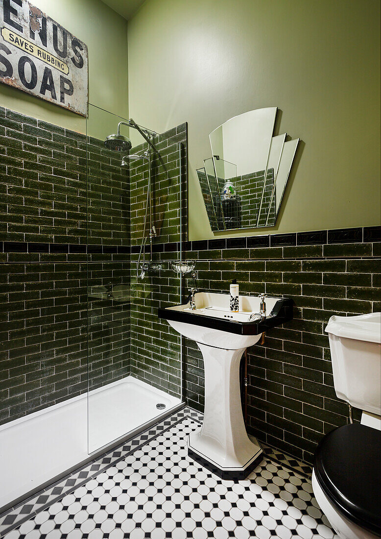 Pedestal washbasin and shower area in bathroom with green walls and wall tiles