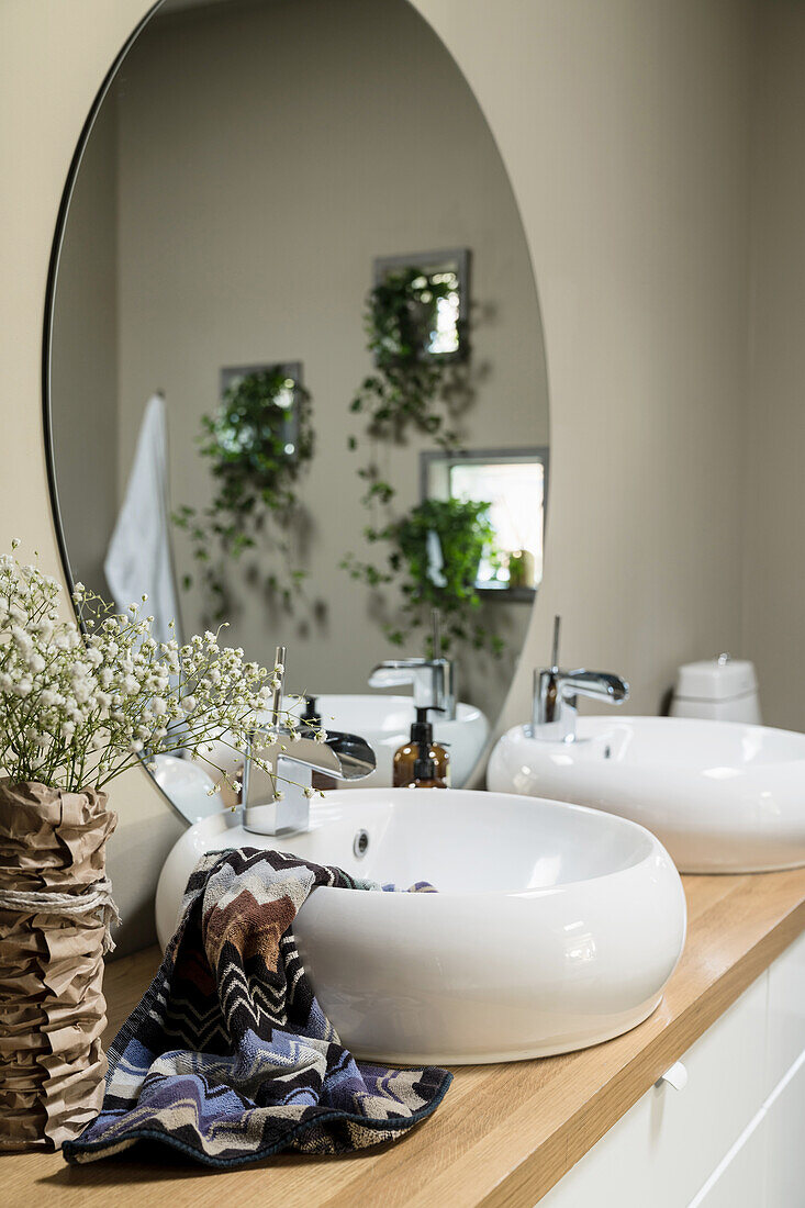 Washstand with round countertop basins and round mirror in bathroom