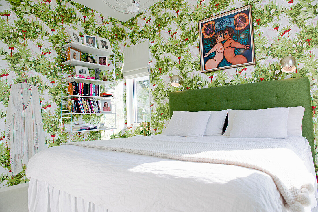 Doppelbett mit grünem Betthaupt und Bücherregal im Schlafzimmer mit Blumentapete