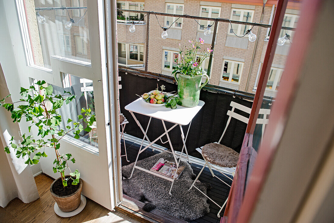 Kleiner Tisch mit Stühlen auf sommerlichem Balkon