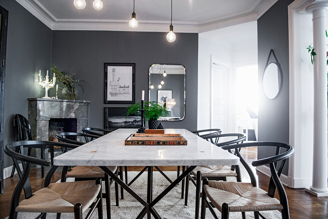 Classic chairs around dining table with marble top in room with grey walls