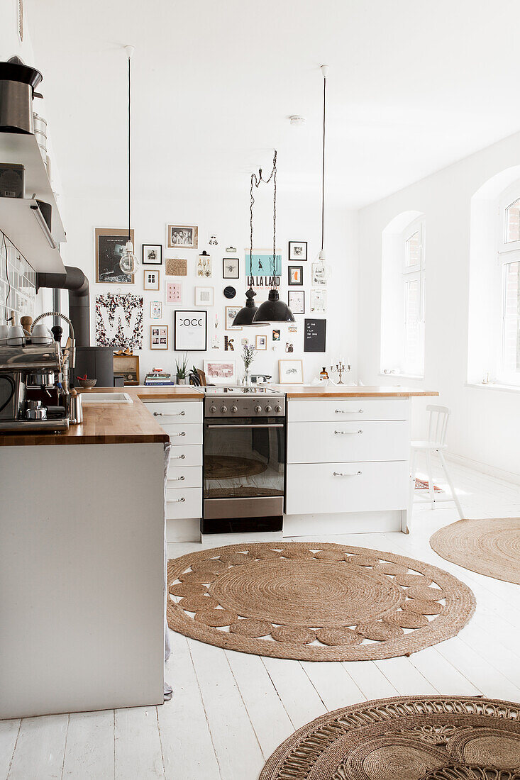 Weiße Küche mit Pendelleuchten, runden Teppichvorlegern und Dielenboden