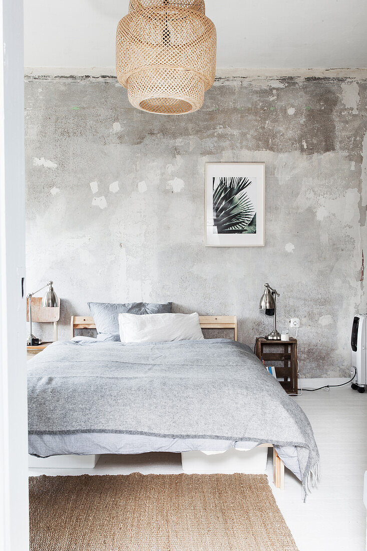 Doppelbett im Schlafzimmer mit abgeblätterter Wandfarbe
