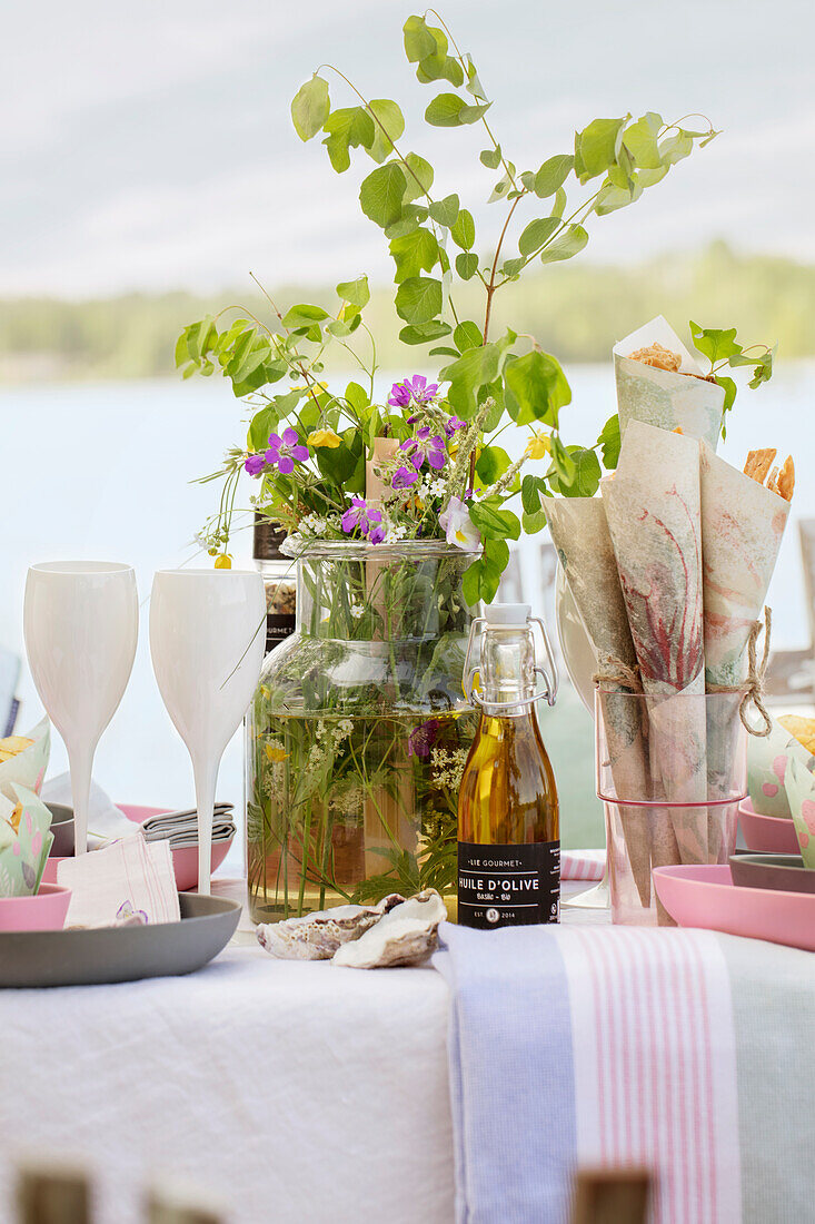 Table festively set with bouquet of wild flowers by a lake