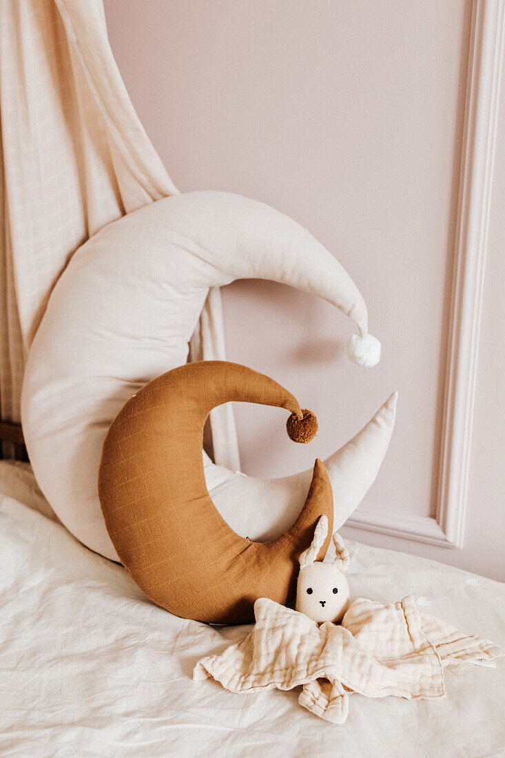 Mondkissen und Puppe auf Kinderbett