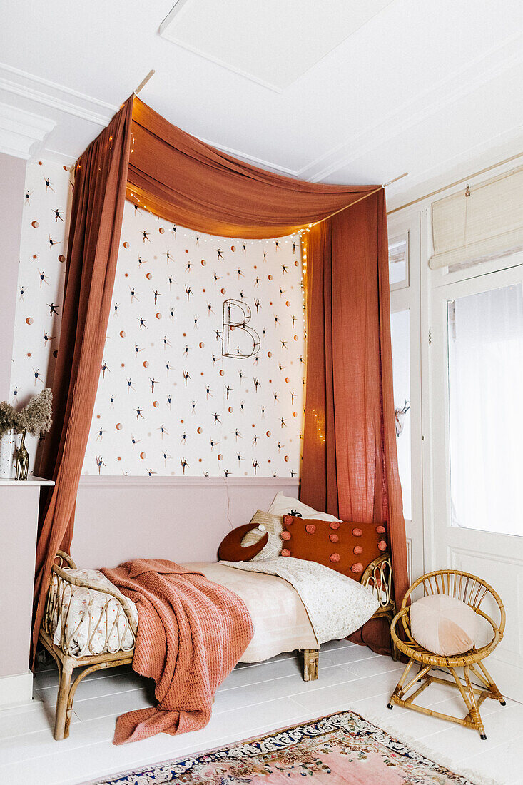 A children's room in terracotta tones with a bed with a canopy