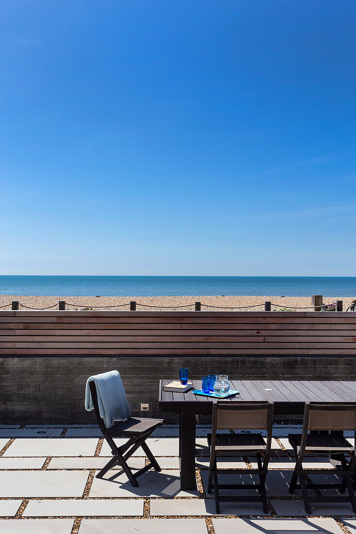 Tisch und Stühle auf der Terrasse mit Meerblick bei blauem Himmel