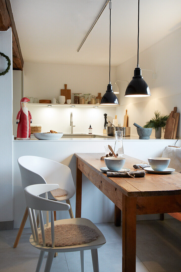 Small kitchen with wooden table, modern chairs and black pendant lights