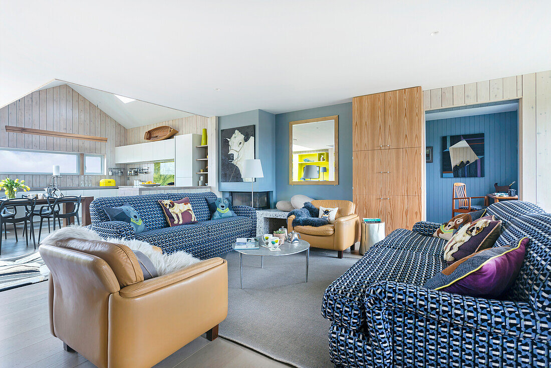 Offener Wohnraum mit blau-weiß bezogenen Sofas und hellbraunen Ledersesseln