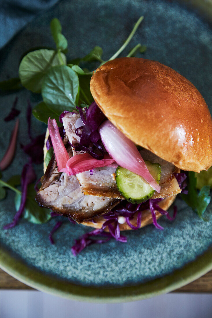 Burger mit gegrilltem Fleisch und rotem Krautsalat auf Keramikteller